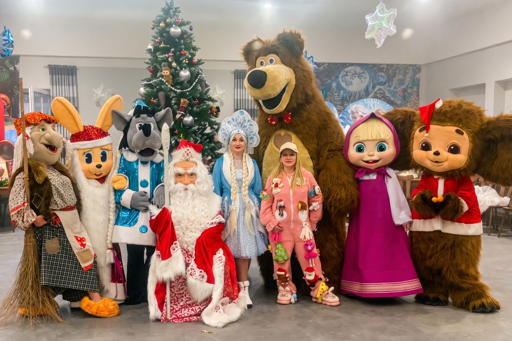 Väterchen Frost und Snegurotschka mit Maskottchen am Weihnachtsbaum